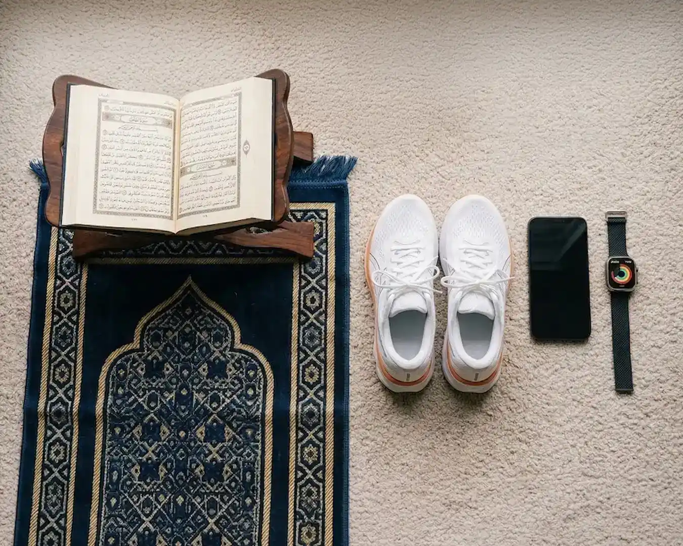 flat lay of prayer mat, quran, running shoe, iphone and apple watch